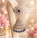Silver jhumka earring with sapphire-blue stones on a velvet stand